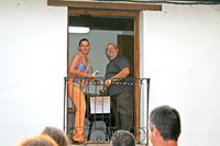 Alcaldesa y párroco lanzando los productos desde el balcón