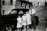 Foto de tres niñas y un hombre junto a un coche negro