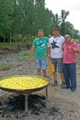 Paella a frente y tres cocineros al fondo